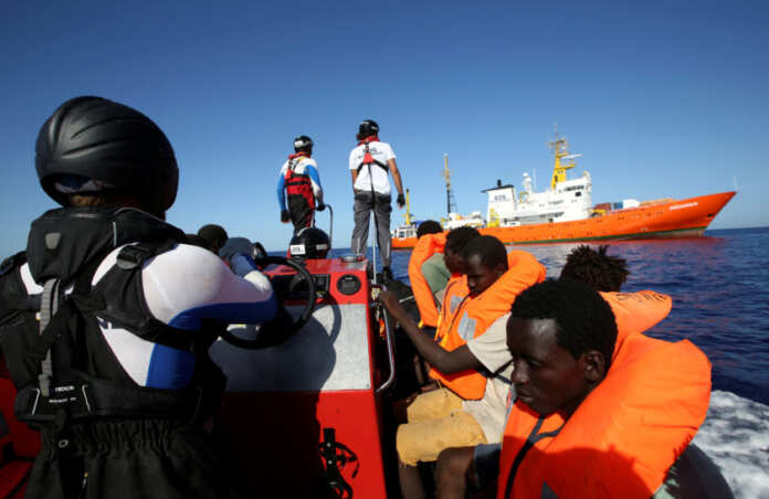FILE PHOTO: Migrants on a rubber boat are rescued by the SOS Mediterranee organisation during a search and rescue (SAR) operation with the MV Aquarius rescue ship (background) in the Mediterranean Sea, off the Libyan Coast