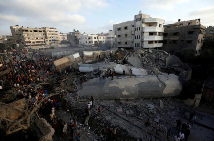 Palestinians gather around a building after it was bombed by an Israeli aircraft, in Gaza City