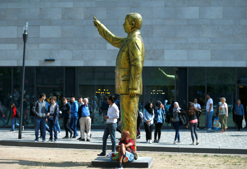 People stand near a statue of Turkish President Tayyip Erdogan during the art exhibition