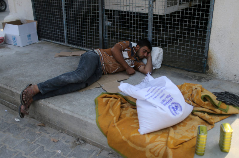 Palestinian man rests at an aid distribution center run by UNRWA in Khan Younis in the southern Gaza Strip