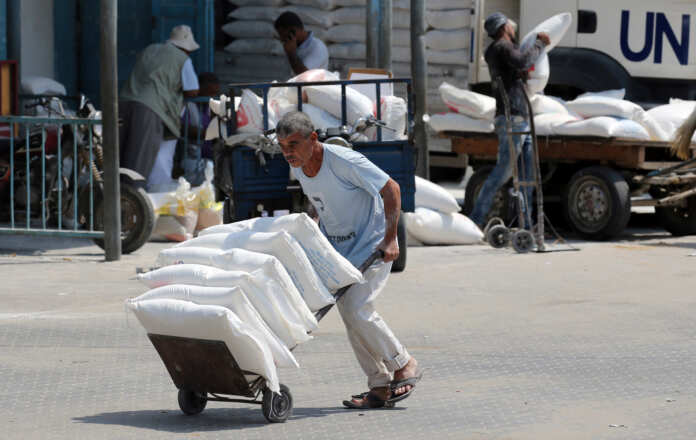 Palestinian man pushes a cart with bags of flour at an aid distribution center run by UNRWA in Khan Younis