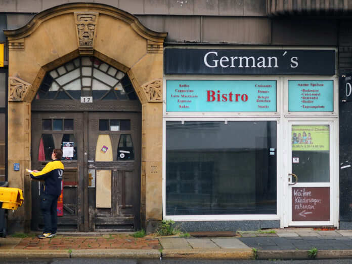 A postwoman stands at a house door in Chemnitz Pressjoni sorveljanza partit lemin Ġermanja