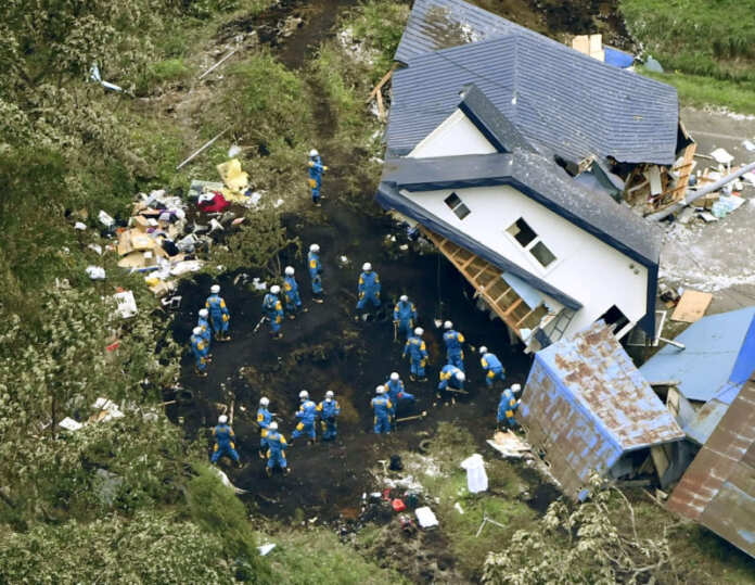 Police officers search for survivors from a house damaged by a landslide caused by an earthquake in Atsuma town