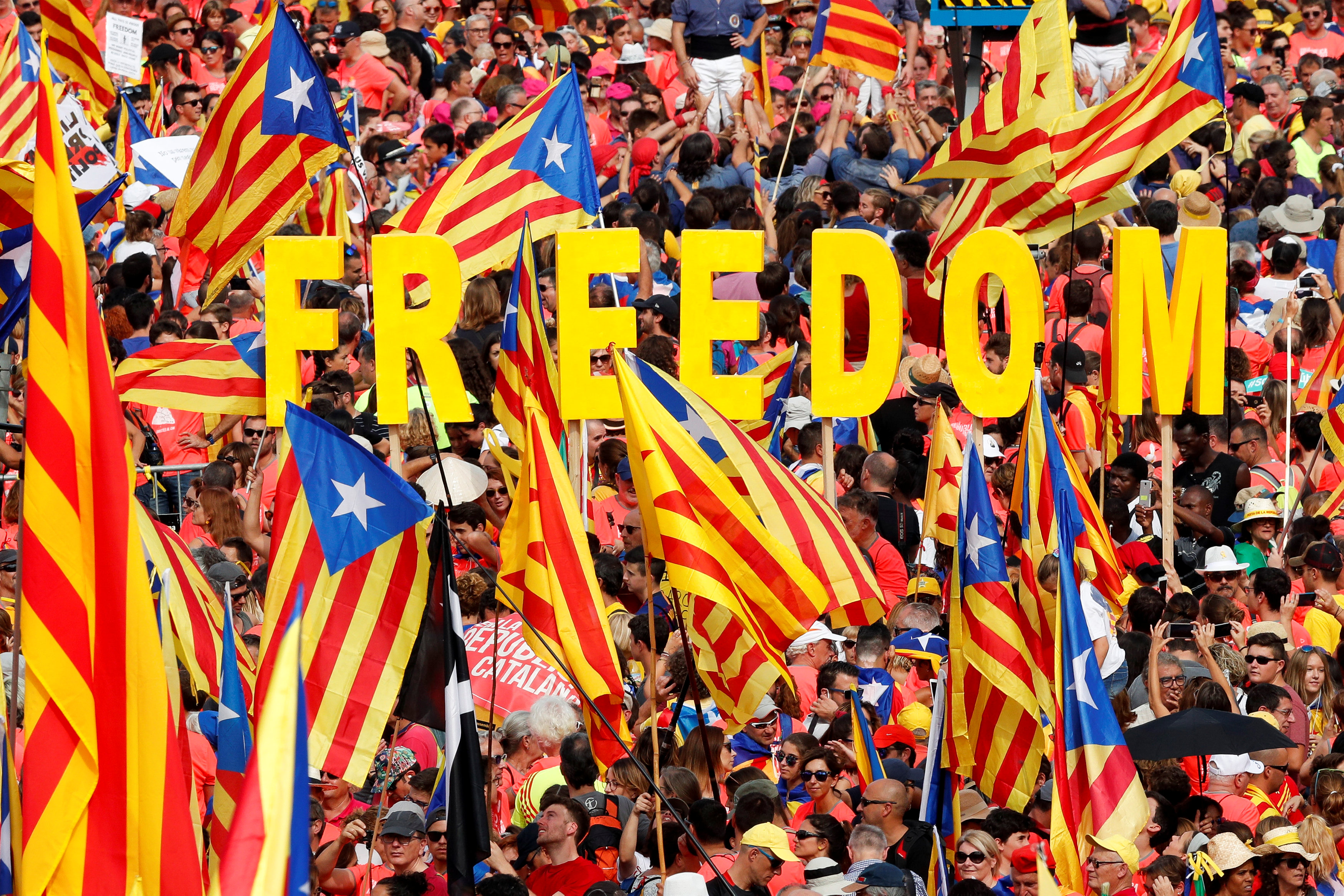 People hold up Catalan separatist flags and letters spelling out