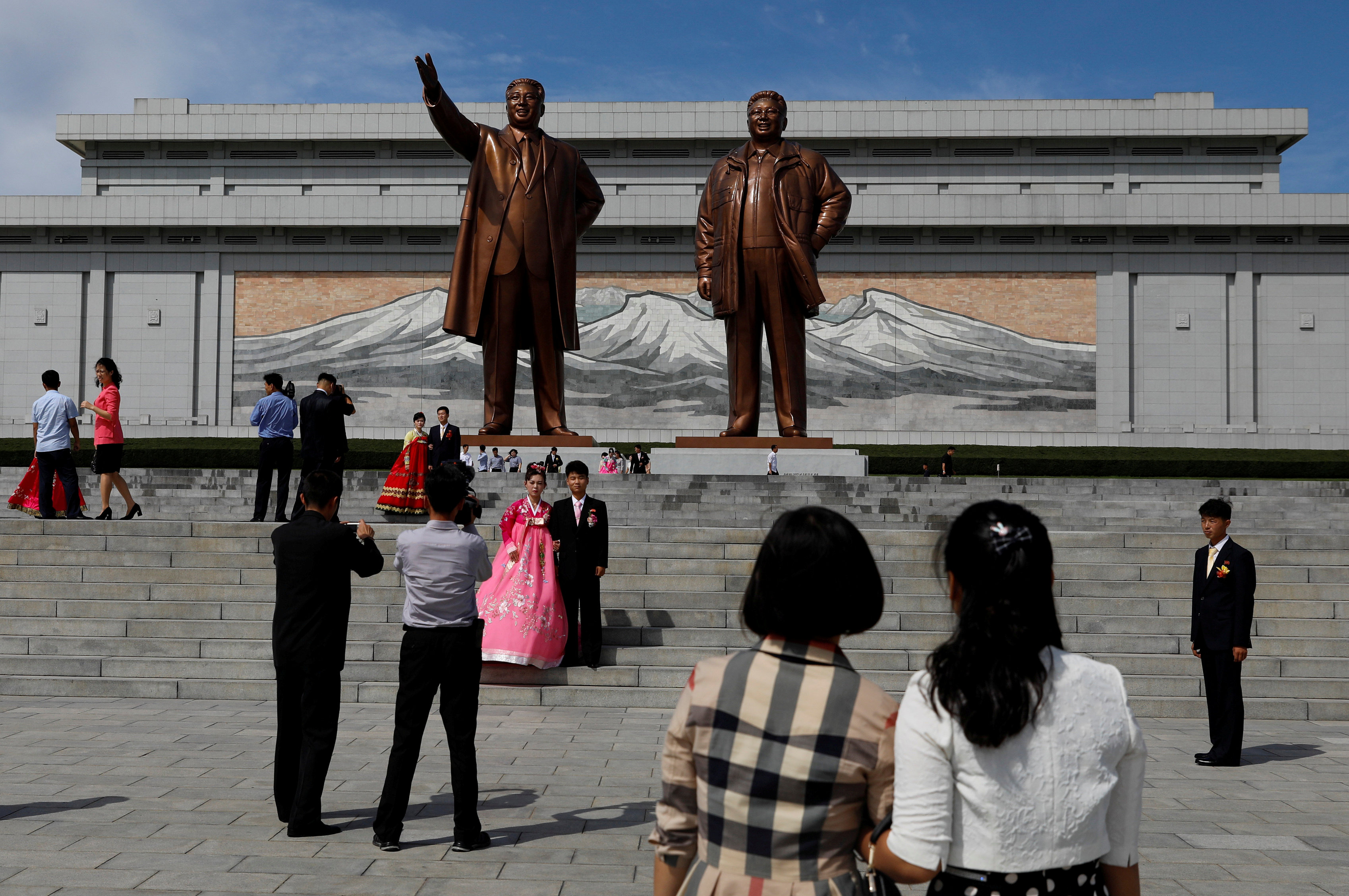 FILE PHOTO: People take photos after paying their respects in front of bronze statues of the late leaders Kim Il Sung and Kim Jong Il before getting married in Pyongyang