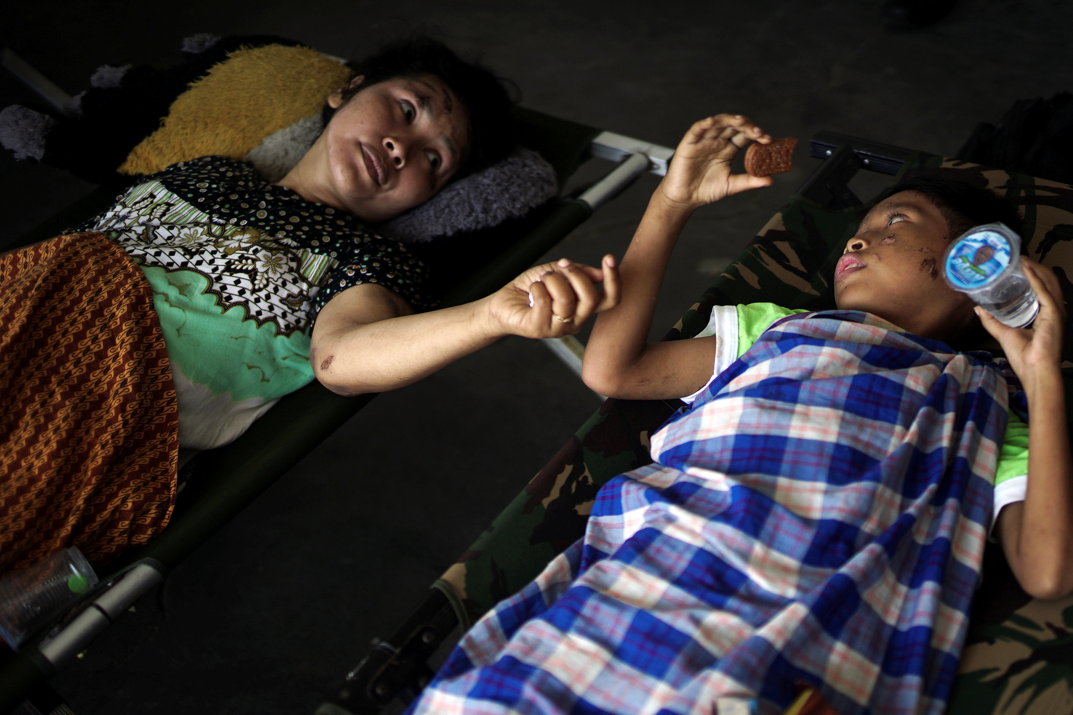 A mother and her son, both injured by the earthquake and tsunami, wait to be airlifted out by a military plane at Mutiara Sis Al Jufri Airport in Palu