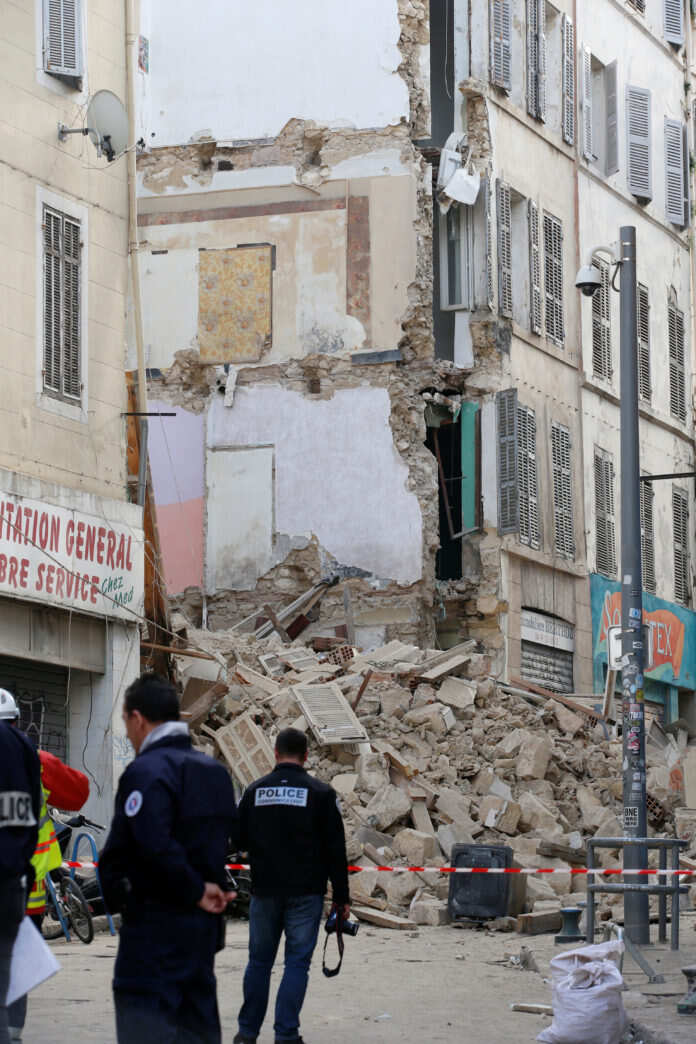 French police and rescue workers are seen near rubble after buildings collapsed in central Marseille