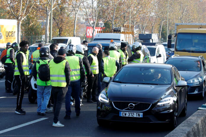 People wearing yellow vests, a symbol of a French drivers' protest against higher fuel prices, gather to block the ring road in Paris