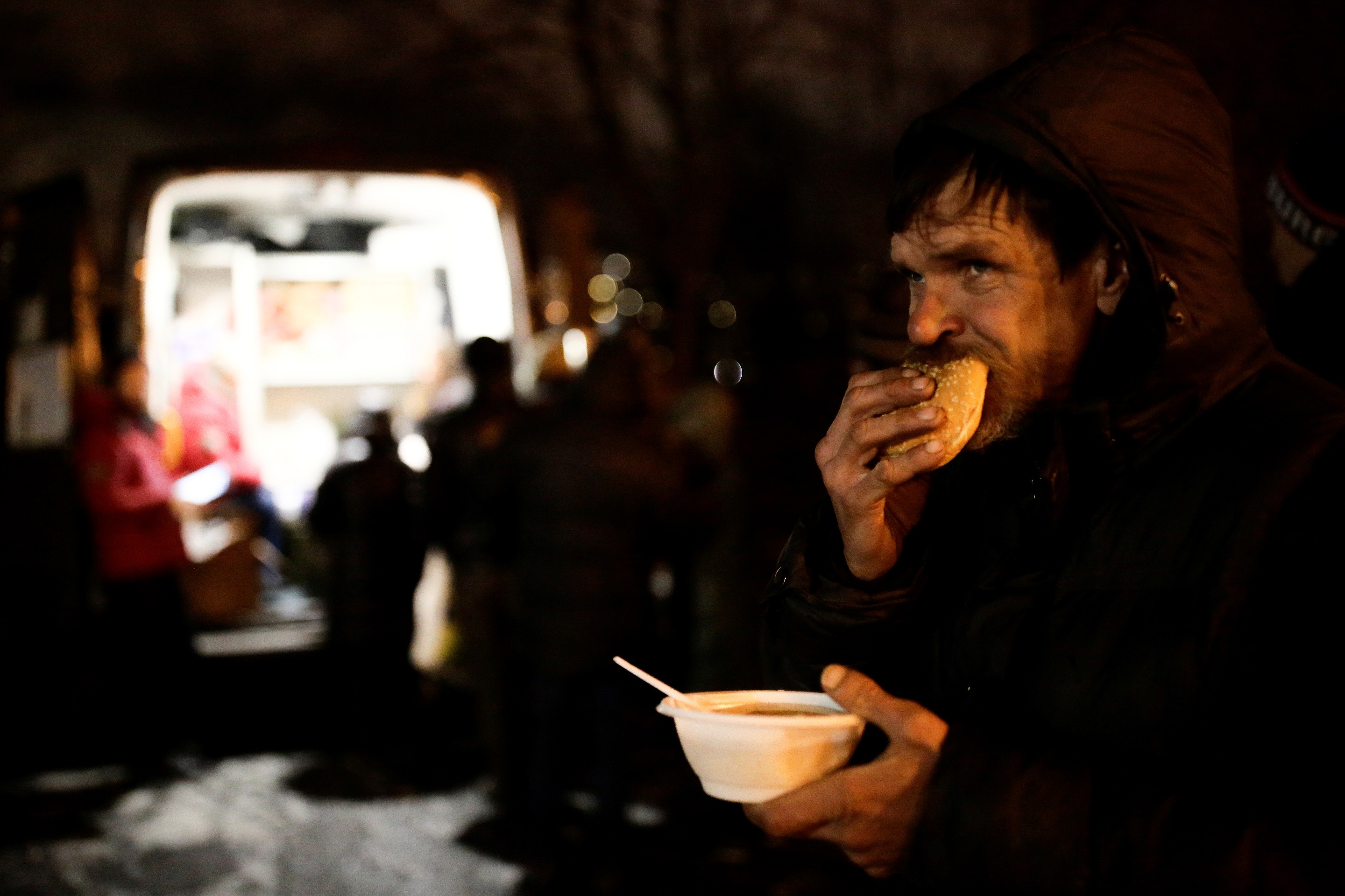 A man eats soup and bread as volunteers distribute charity meals for homeless people in St. Petersburg