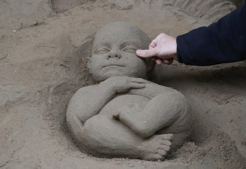 An artist works on a sand sculpture representing baby Jesus as a part of nativity scene in St. Peter's square at the Vatican