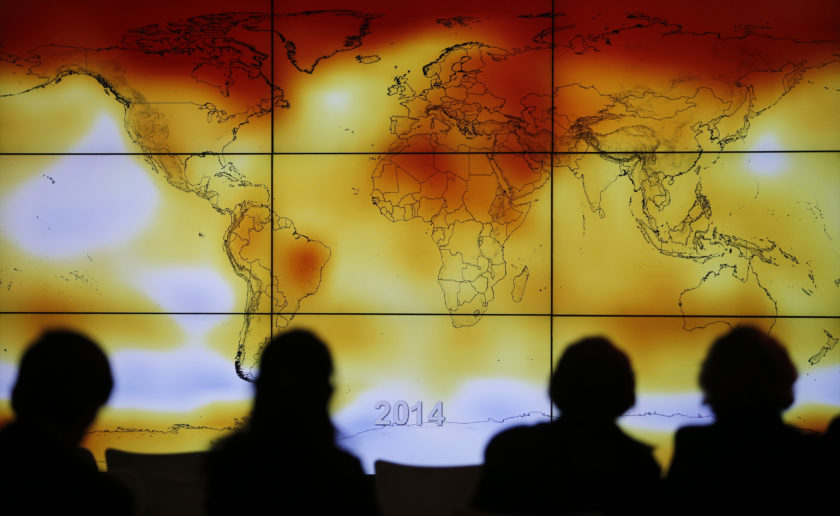 Participants looks at a screen projecting a world map with climate anomalies during the World Climate Change Conference 2015 (COP21) at Le Bourget