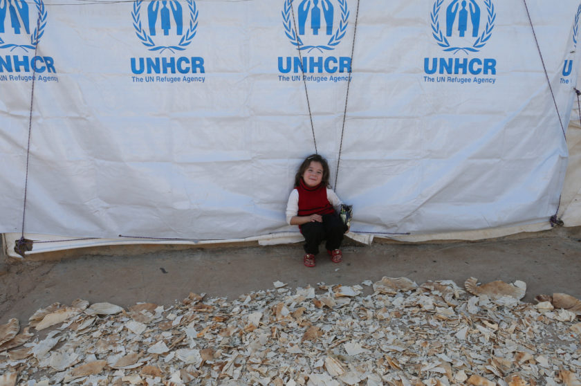 A Syrian refugee girl sits next to dried bread at a refugee camp in Akkar