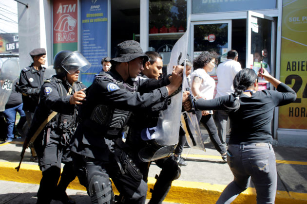Riot police dislodge journalists from the main entrance to police headquarters in Managua