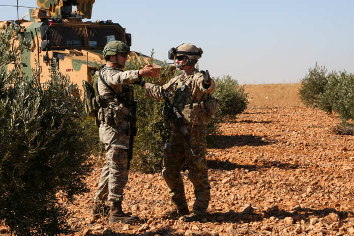 U.S. and Turkish soldiers discuss details during the first-ever combined joint patrol in Manbij