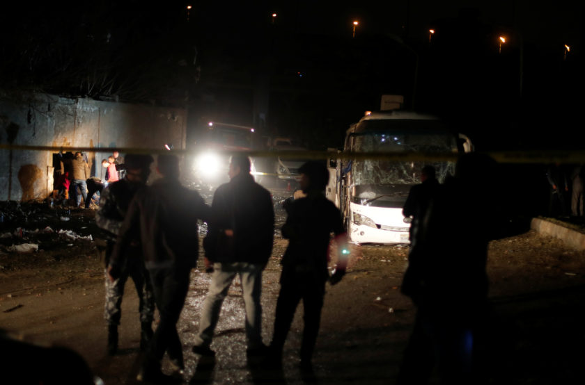 Police officers inspect a scene of a bus blast in Giza
