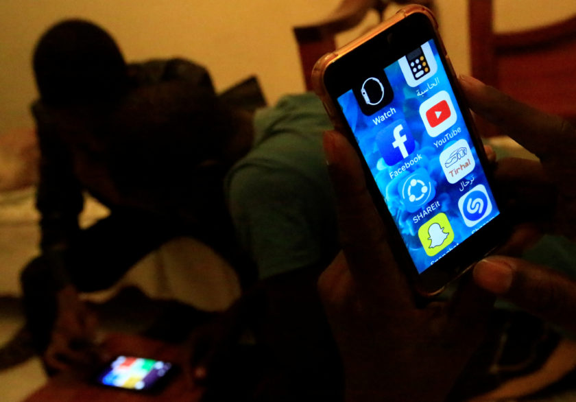 A Sudanese man holds his phone with restricted internet access social media platforms, in Khartoum