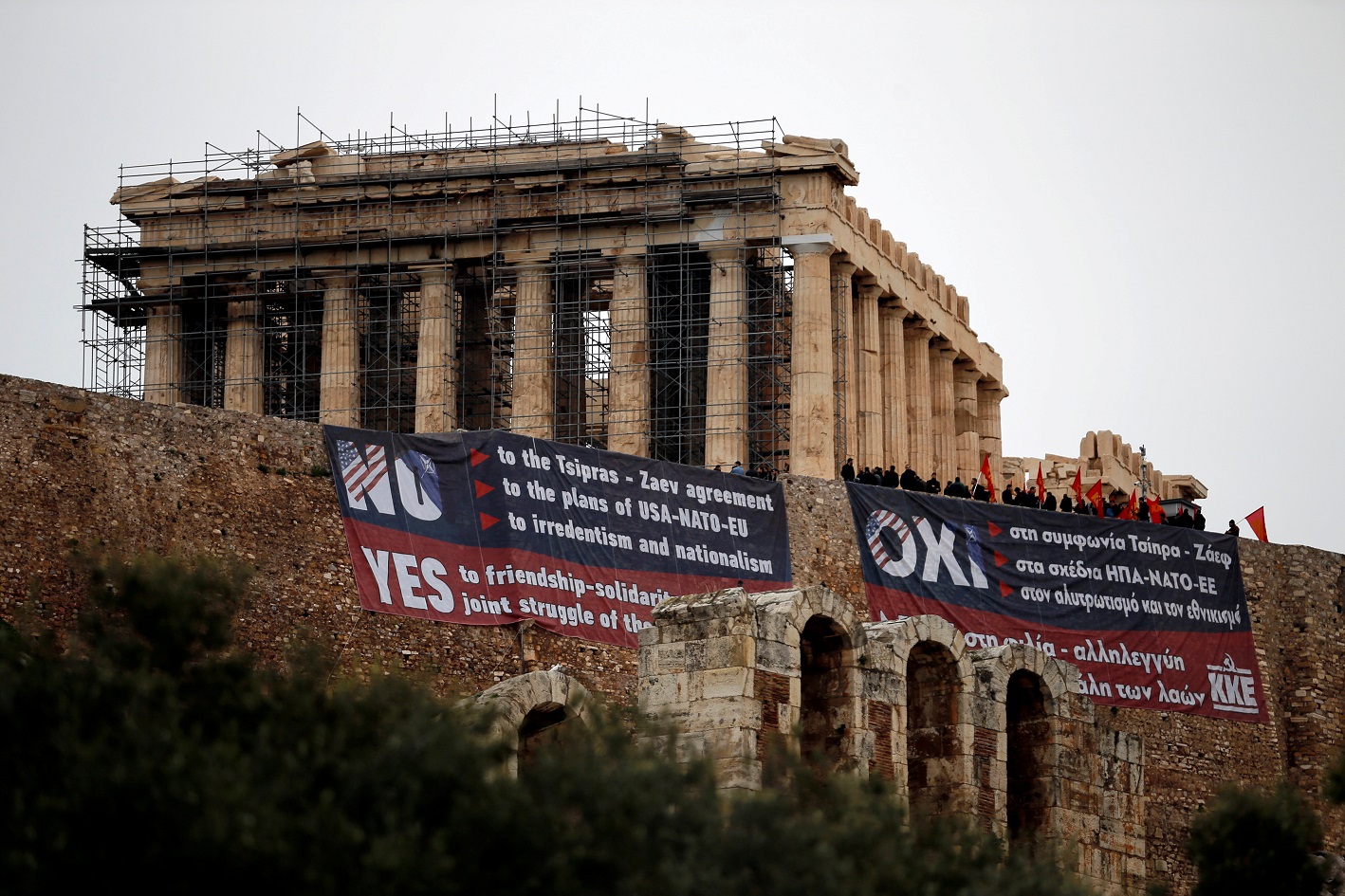 Members of the Greek Communist Party hang banners in English and Greek against the agreement reached by Greece and Macedonia to resolve a dispute over the former Yugoslav republic's name, next to the Parthenon temple atop the Acropolis Hill, in Athens