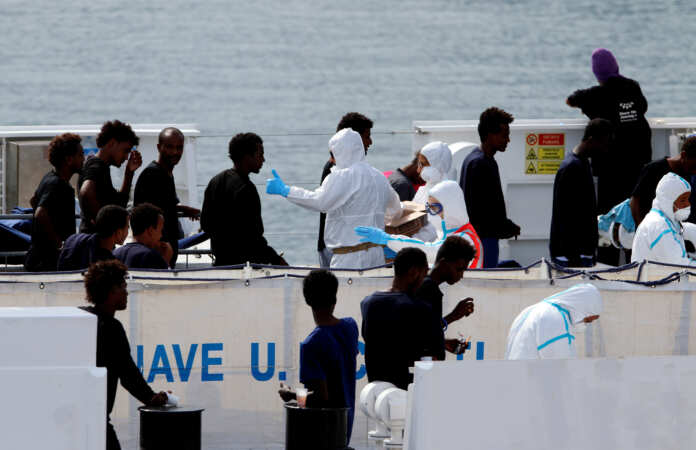 FILE PHOTO: Migrants wait to disembark from the Italian coast guard vessel
