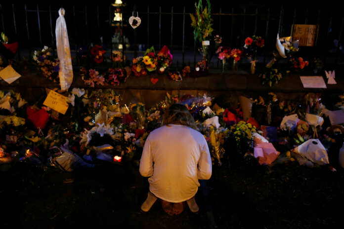 A man prays at a flower tribute area at Botanical Gardens in Christchurch