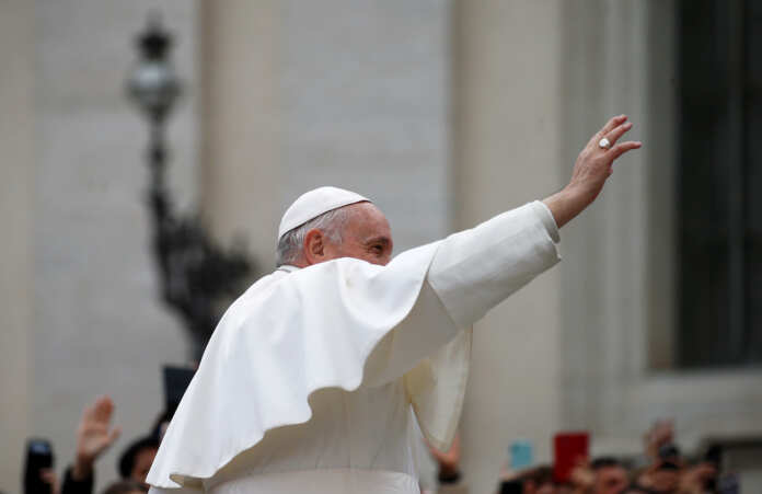 Pope Francis waves to crowds in St. Peter's square during the weekly general audience at the Vatican