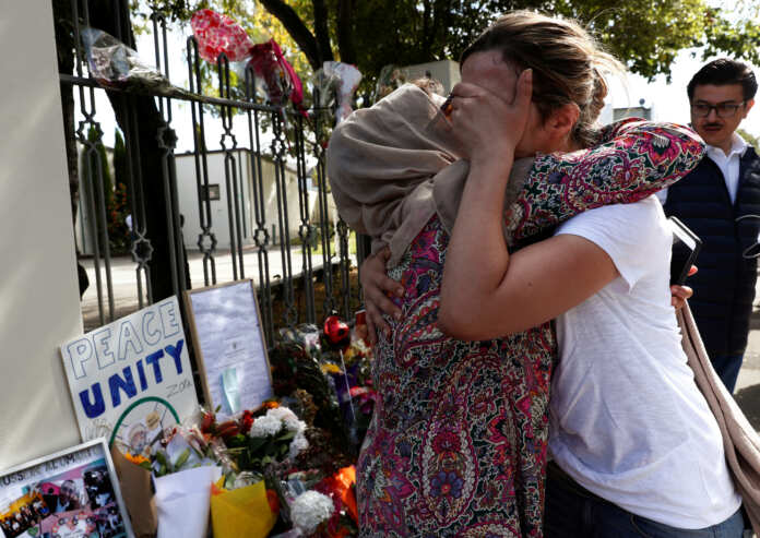 A woman cries next to a tribute to victim Hussein Al-Umari outside Al-Noor mosque after it was reopened in Christchurch