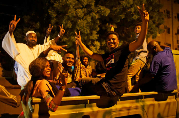 Sudanese demonstrators celebrate after the Defence Minister Awad Ibn Auf stepped down as head of the country's transitional ruling military council, as protesters demanded quicker political change, outside the Defence Ministry in Khartoum