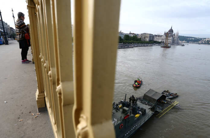 A woman watches as divers arrive at a rescue vessel near the site of a boat accident, which killed several people, on the Danube river in Budapest