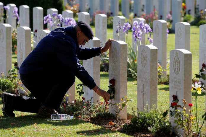 A man places a flower on a tomb before the Royal British Legion’s commemoration ceremony for the 75th anniversary of D-Day, at the Commonwealth War Cemetery in Bayeux