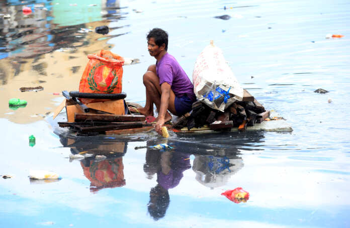 FILE PHOTO: Man uses an improvised banca to collect plastic materials in a polluted river in Manila