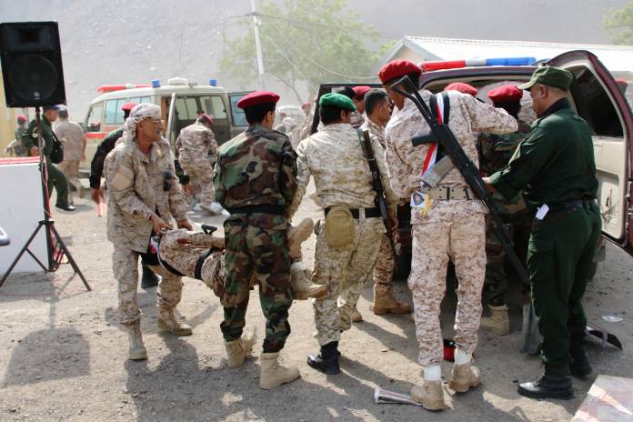Soldiers carry the injured following a missile attack on a military parade during a graduation ceremony for newly recruited troopers in Aden