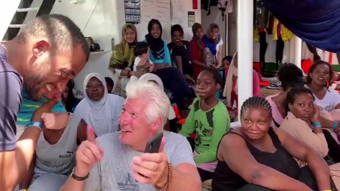 U.S. actor Gere talks to a rescued migrant aboard Open Arms rescue boat at Mediterranean sea