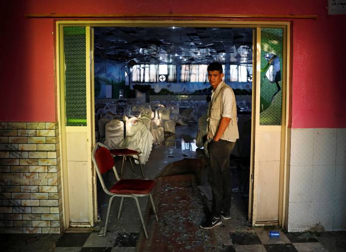 An Afghan man inspects a damaged wedding hall after a blast in Kabul, Afghanistan