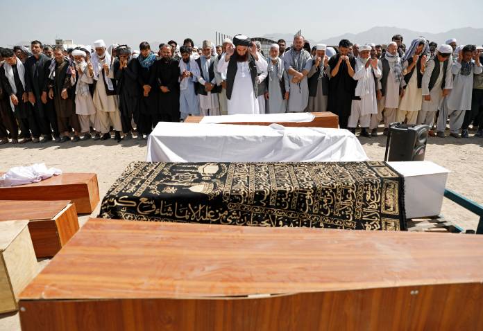 Afghan men offer funeral prayers over the coffins of the victims of a blast in a wedding in Kabul