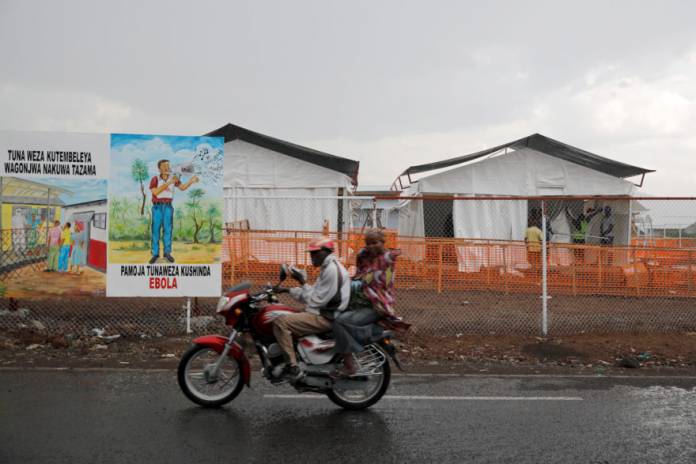 Congolese people ride a motorcycle past the newly constructed MSF Ebola treatment centre in Goma