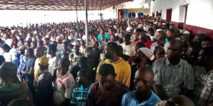 People wait for the start of prayers at a mosque after a fire swept through a school, killing children in Monrovia