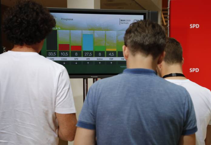 Journalists watch first exit polls on a TV screen at the Social Democratic Party (SPD) headquarters following the regional state elections in Saxony and Brandenburg in Berlin