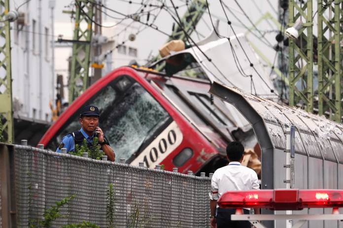 Police are seen on site after a train derailed during a collision with a truck in Yokohama, near Tokyo, Japan