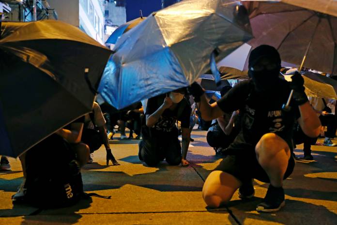 Anti-extradition bill protesters take cover from rubber bullets as they surround Mong Kok police station in Hong Kong