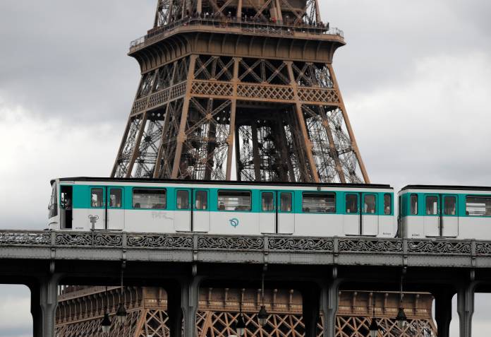An elevated Metro passes over a bridge next to the Eiffel Tower in Paris on the eve of a strike against pension reform plans