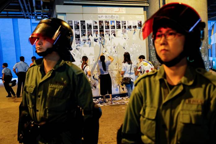 Riot police are seen in front of pro-China supporters as they pull down