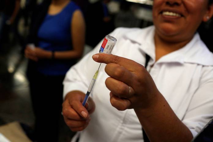 A nurse fills a syringe before administering an injection for seasonal flu in Mexico City