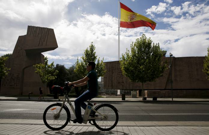 FILE PHOTO: A man rides past Discovery Monument as a huge Spanish flag flutters in Madrid