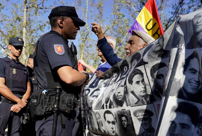 A man talks to a police officer during a protest outside Madrid's Supreme Court calling on the government to ban the burial of the Spanish dictator Francisco Franco in the Almudena Cathedral in Madrid