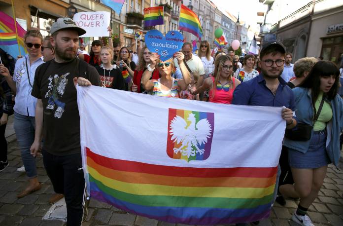 Bartosz Staszewski and his partner Slawomir Wodzynski carry a flag as they attend a Pride march in the town of Kalisz