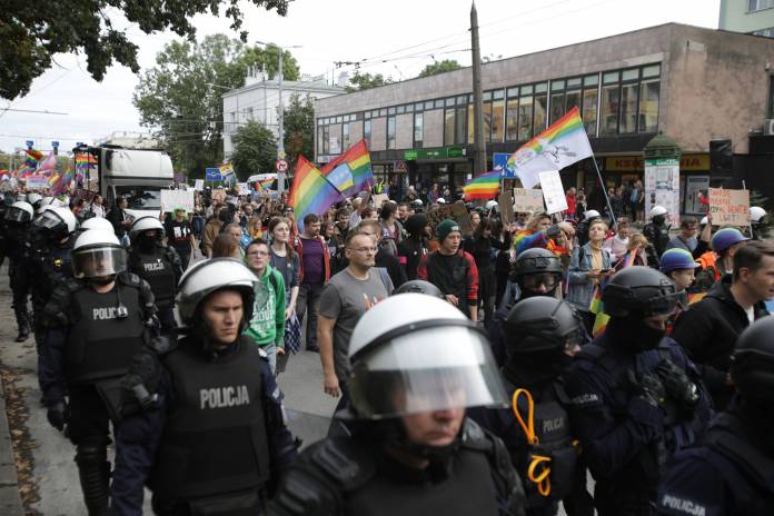Police walk next to participants in Pride march in Lublin