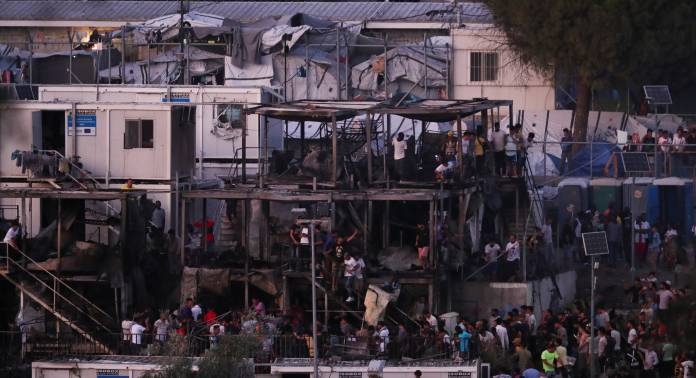 Migrants climb on burnt containers following a fire in Moria camp on the island of Lesbos