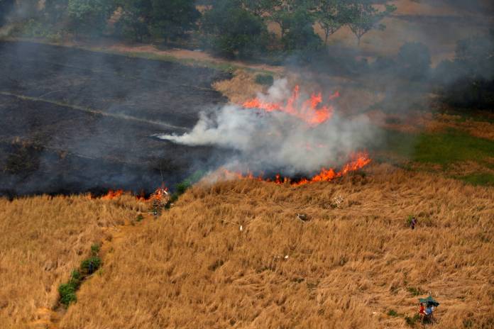 People sit in a hut as land burns near Banjarmasin in South Kalimantan province