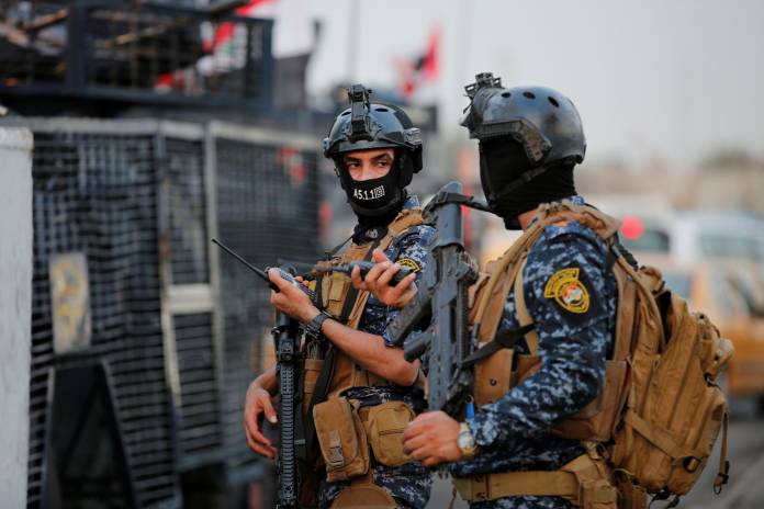 Members of Iraqi federal police are seen with military vehicles in a street in Baghdad