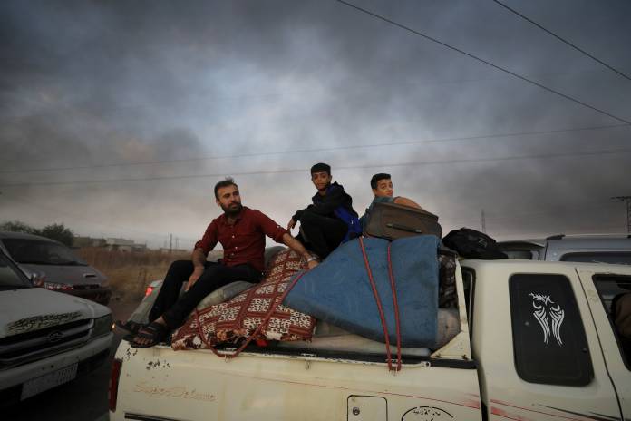 FILE PHOTO: People sit on belongings at a back of a truck as they flee Ras al Ain town