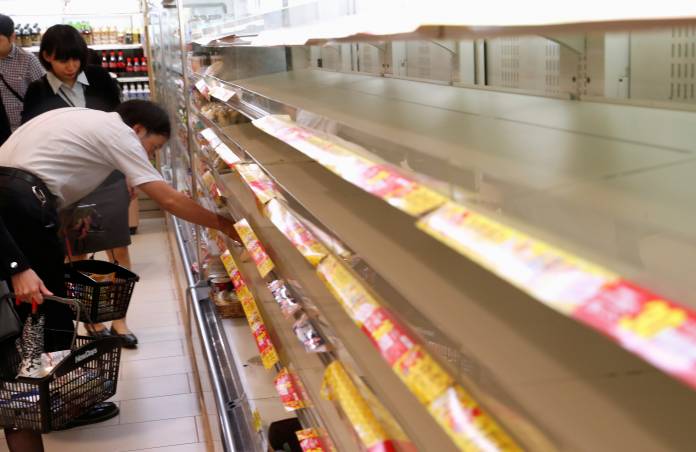 A customer looks for food on the racks inside a convenience store at Tokyo Station in Tokyo, Japan, ahead of Typhoon Hagibis